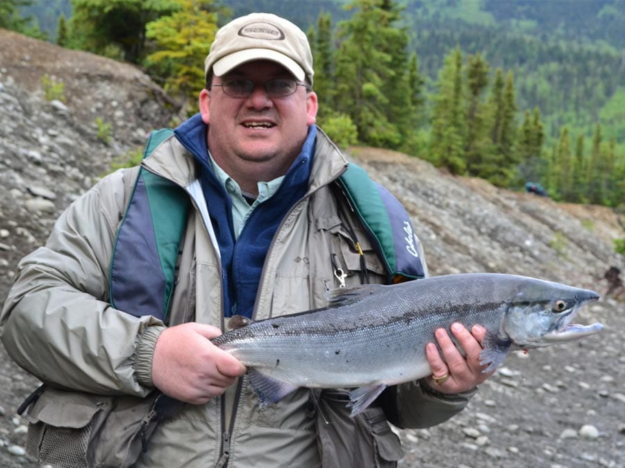 A man poses with a salmon.