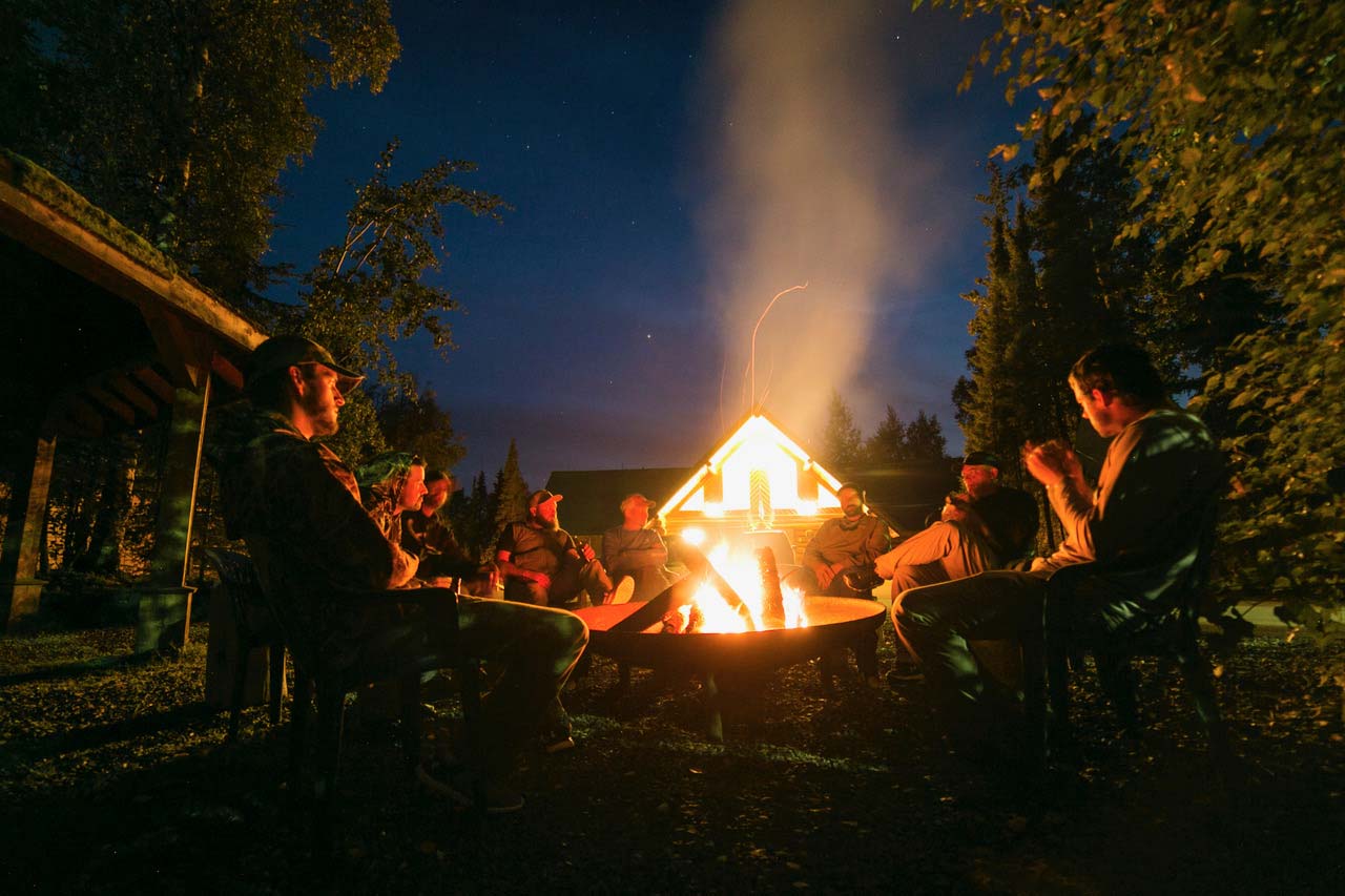 Group of outdoor enthusiasts around evening fire pit